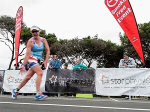 Triathlete competing at Busselton Ironman with Star Physio sponsorship signage during endurance race in Western Australia